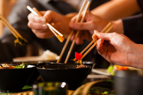 アジア料理を食べながら箸を持った中国のグループ。