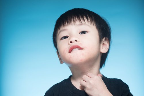 首に手を当てている中国から来た少年。