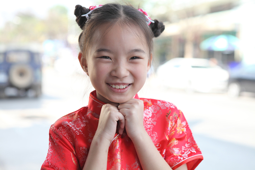 赤いチャイナドレスを着た若い女の子、中国、微笑みます。