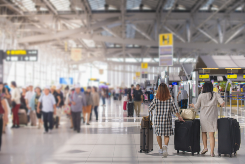 荷物を持って中国の空港を歩く人々のグループ。