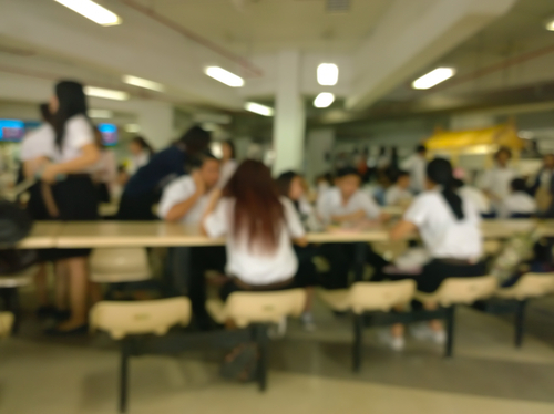 学校のカフェテリアのテーブルに座る中国からの人々のグループ。