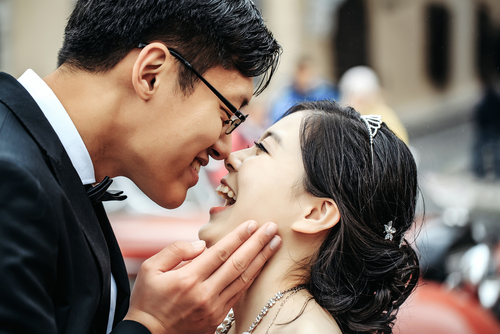 車の前でキスをする新郎新婦。
