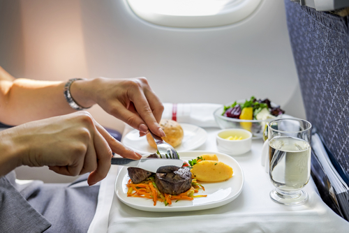 中国の飛行機の中で女性が皿に盛られた食べ物を食べている。