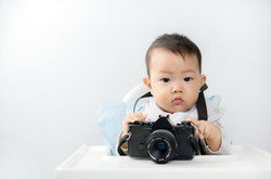 カメラを持ってハイチェアに座り、貴重な瞬間を捉えている赤ちゃん。