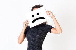 悲しそうな顔の紙を掲げる中国の女性。