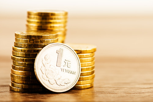 木製のテーブルの上に中国からの円硬貨の山。