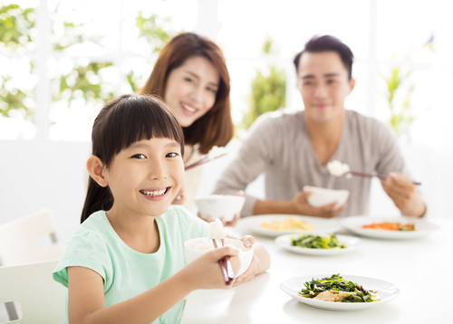 テーブルに座って食事をする家族。
