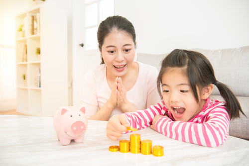 家で貯金箱で遊ぶ母と娘。