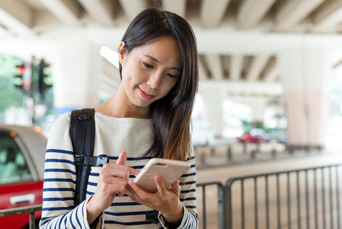 中国から来た若い女性が路上で携帯電話を使用しています。