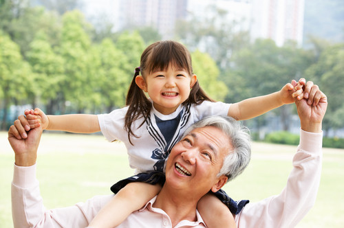 中国の公園で若い女の子が年配の男性に抱かれています。