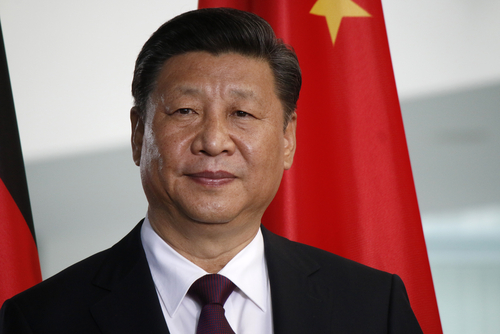中国の習近平国家主席は2つの国旗の前に誇らしげに立っています。