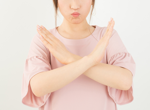 アジアの女性は、白い背景に一時停止の標識を作ります。