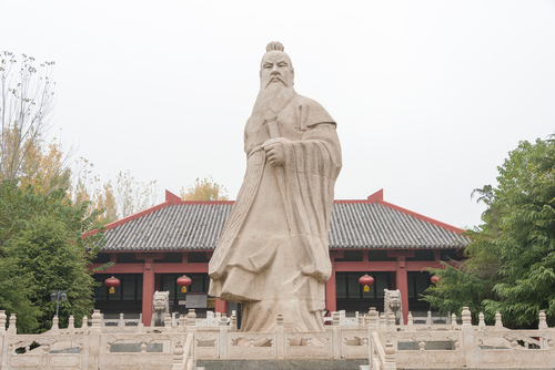 中国の建物の前にある男性の銅像。