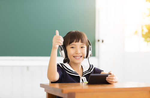 教室で親指を立てる若い中国人の女の子のストックフォトです。