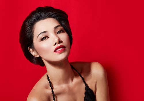 鮮やかな赤い背景にエレガントさをアピールする見事なアジア人女性。