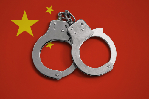 中国の国旗の背景に 2 つの手錠。