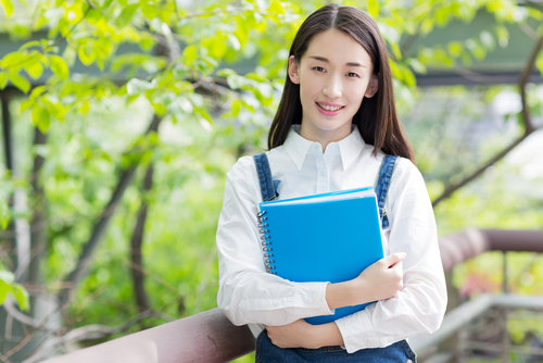 青いフォルダーを持った中国から来たアジア系の若い女の子。