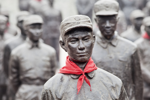 中国にある赤いスカーフをかぶった男性の彫像のグループ。