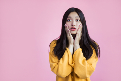 中国から来たアジア系の若い女性が顔に手を当てて驚いている。