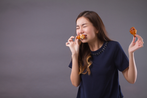 中国の灰色の背景にドーナツを食べる若い女性。