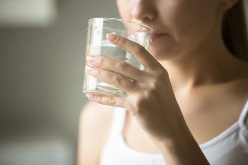 (翻訳: コップ一杯の水を飲む女性。)