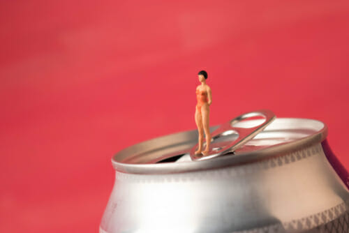 中国のソーダ缶の上に立つ女性。