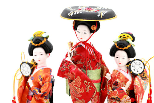 三个中国の芸者の人形が時計を持っています。