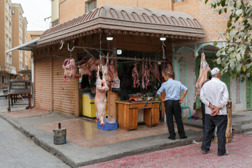 中国の食肉市場の前に立つ二人の男性。