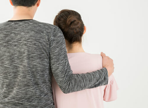 白い背景の前で男性と女性が抱き合っています。