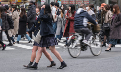 東京の繁華街を渡る人々の群衆。