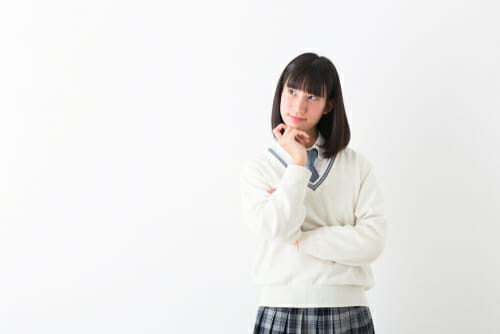顎に手を当ててポーズをとる制服を着た中国の女の子。