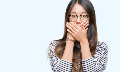 中国から来た若い女性が手で口を覆っている。