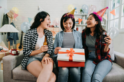 中国の 3 人の友人が誕生日プレゼントを持ってソファに座っています。
