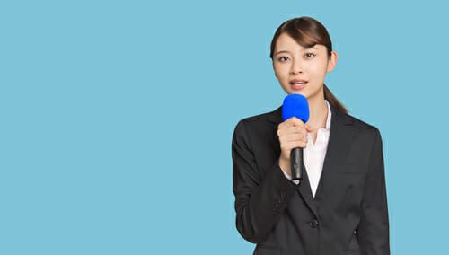 スーツを着た女性がマイクを持っています。