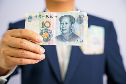 中国元紙幣を持ったスーツを着た男性。