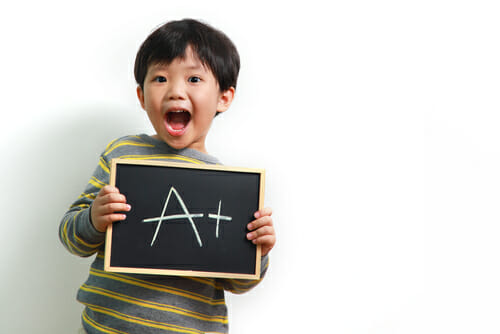 「a」の文字が書かれた黒板を掲げる中国の少年。