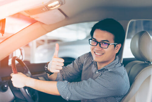 車の運転中に親指を立てる男性。