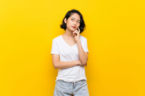 中国の黄色の背景に立つアジアの若い女性。