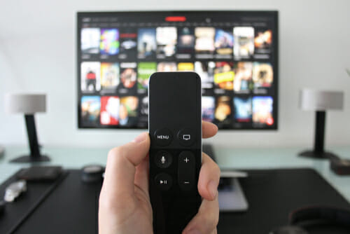 中国のテレビの前でリモコンを持っている人。