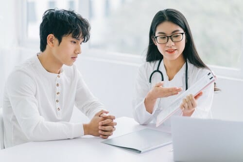(中国人の医師がオフィスで女性患者と話している。) 中国。