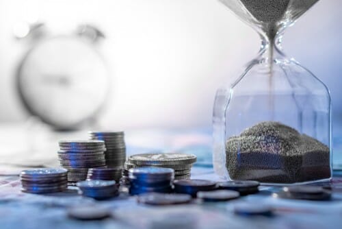 中国の硬貨の山の上に置かれた砂の砂時計。