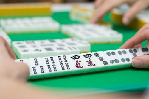 一人の人が绿色桌子の上で中国麻将を遊んでいます。