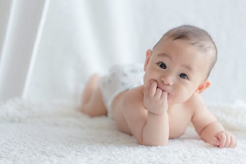 中国では、赤ちゃんが白い毛布の上に横たわっています。