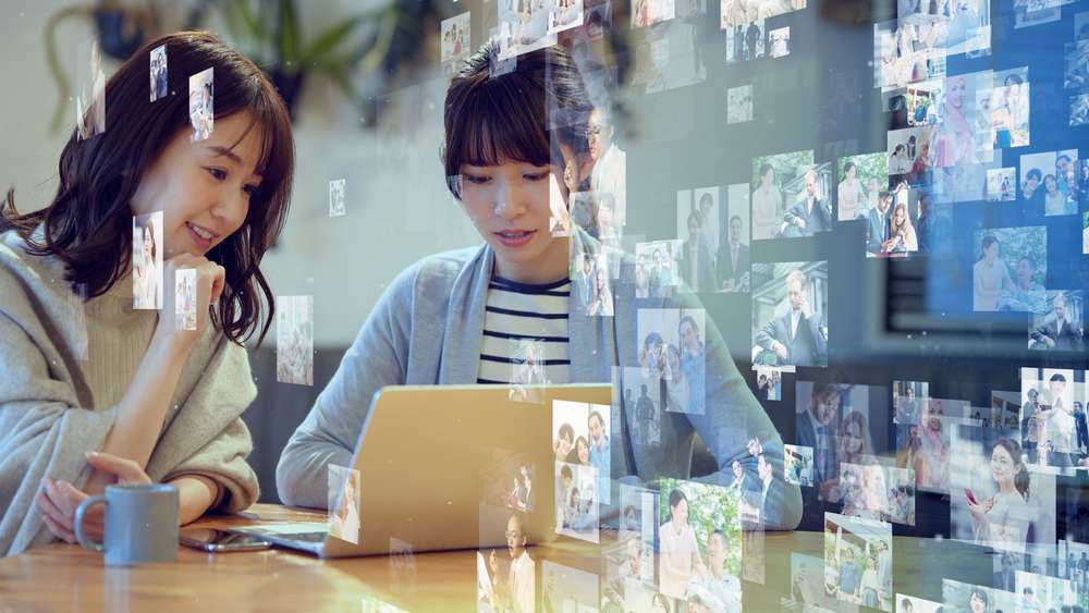 中国でテーブルに座ってラップトップで写真を見ている 2 人の女性。