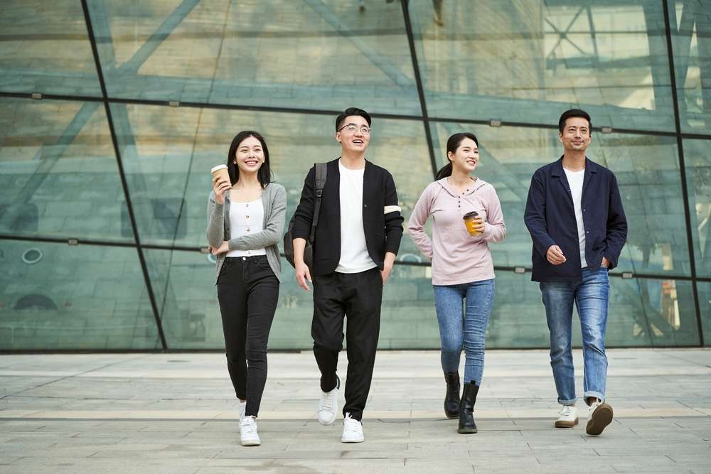 変更された説明: 中国 建物の前を歩くアジア人の学生。