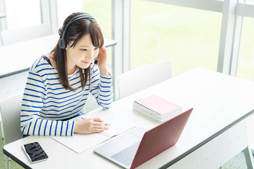 中国でヘッドフォンを着用してラップトップで作業している女性。