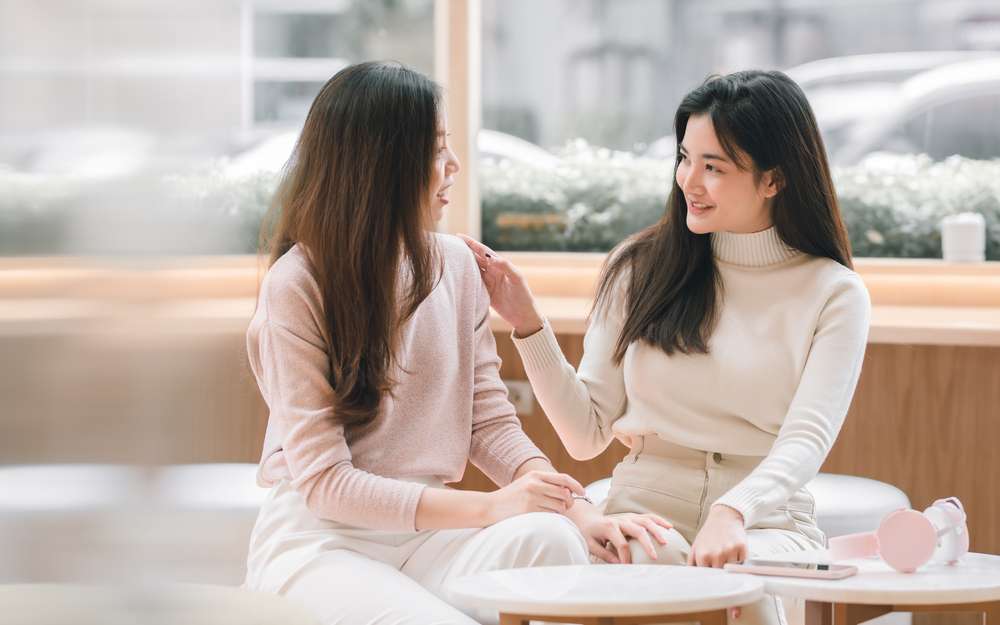 テーブルに座って会話する 2 人のアジア人女性。