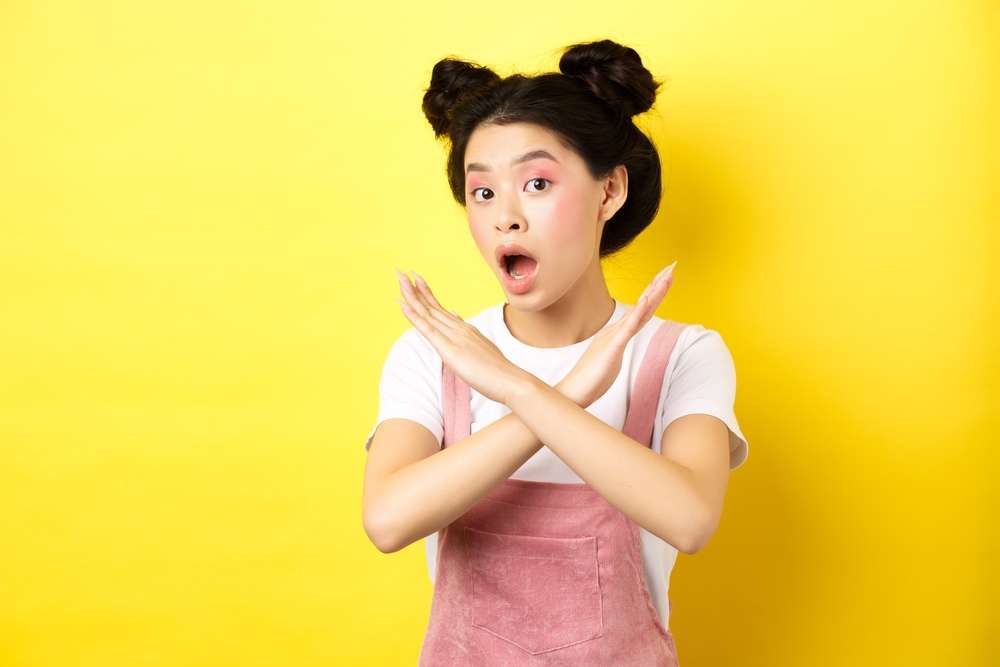 中国の黄色の背景に驚いた表情をしたアジア系の若い女性。