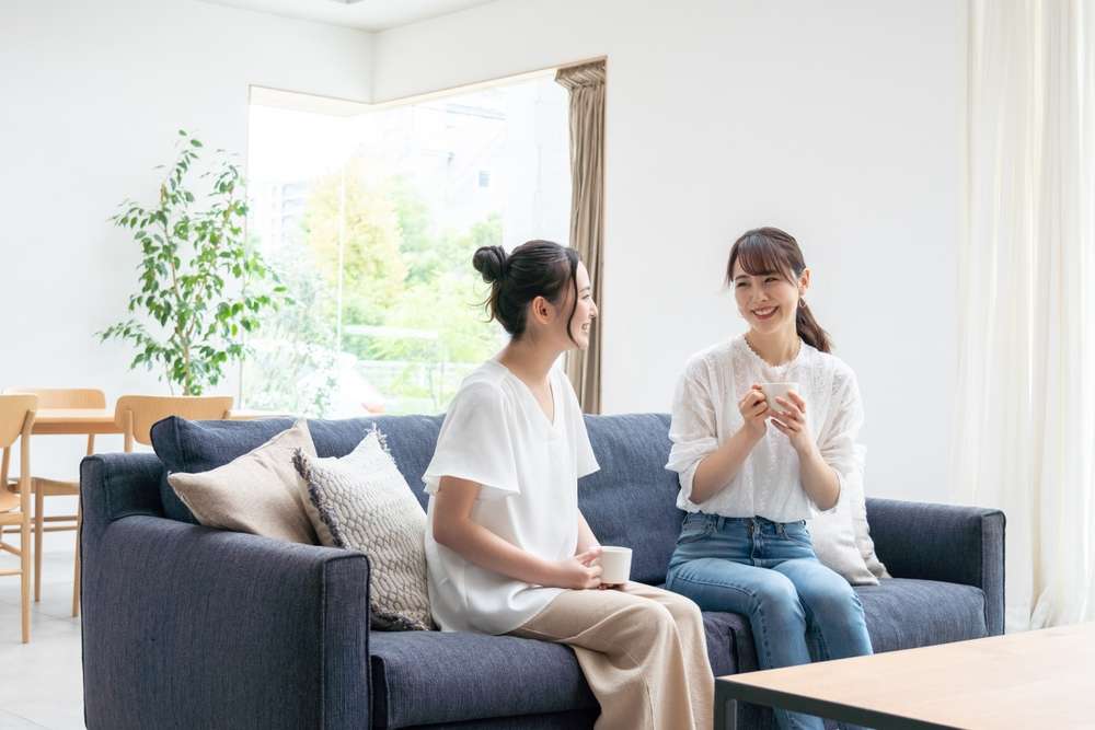 中国の 2 人の女性がリビング ルームのソファに座っています。
