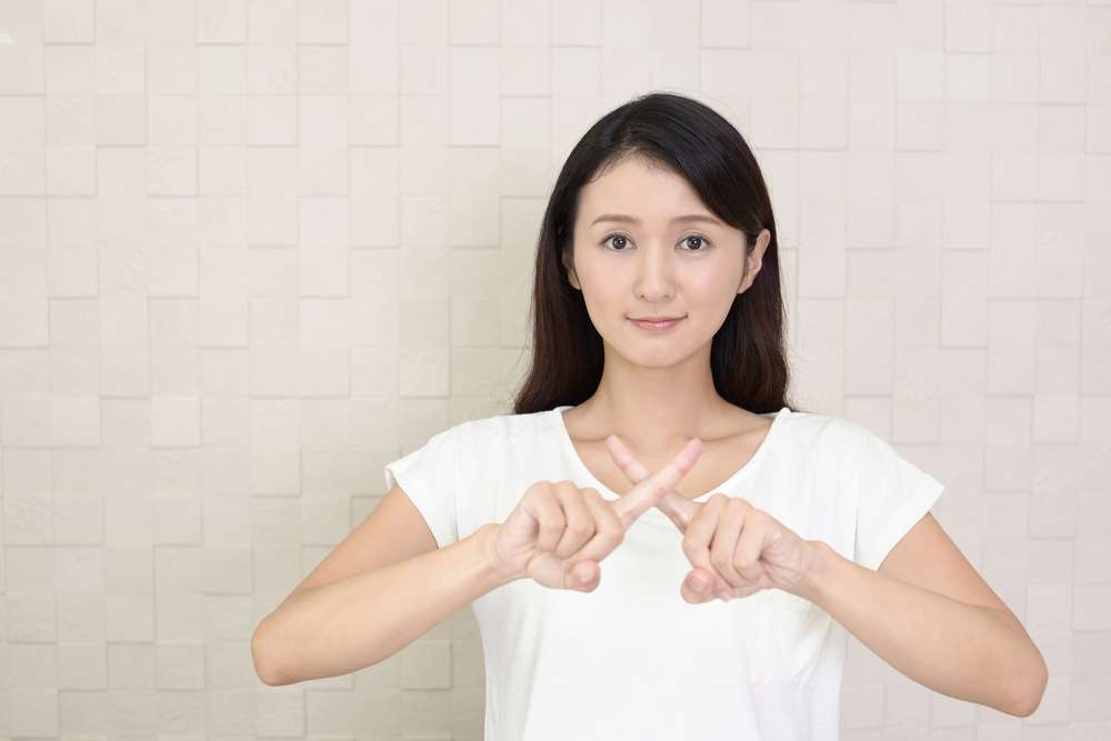 手でサインをする若い中国人女性。